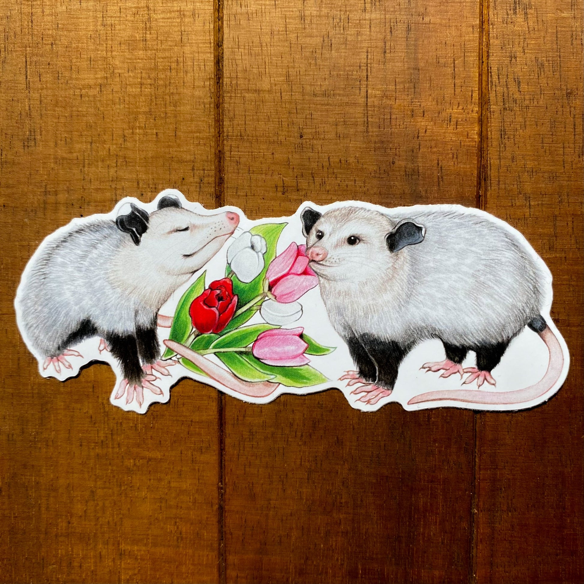 A weatherproof vinyl sticker showing an opossum presenting its partner with a bouquet of tulips