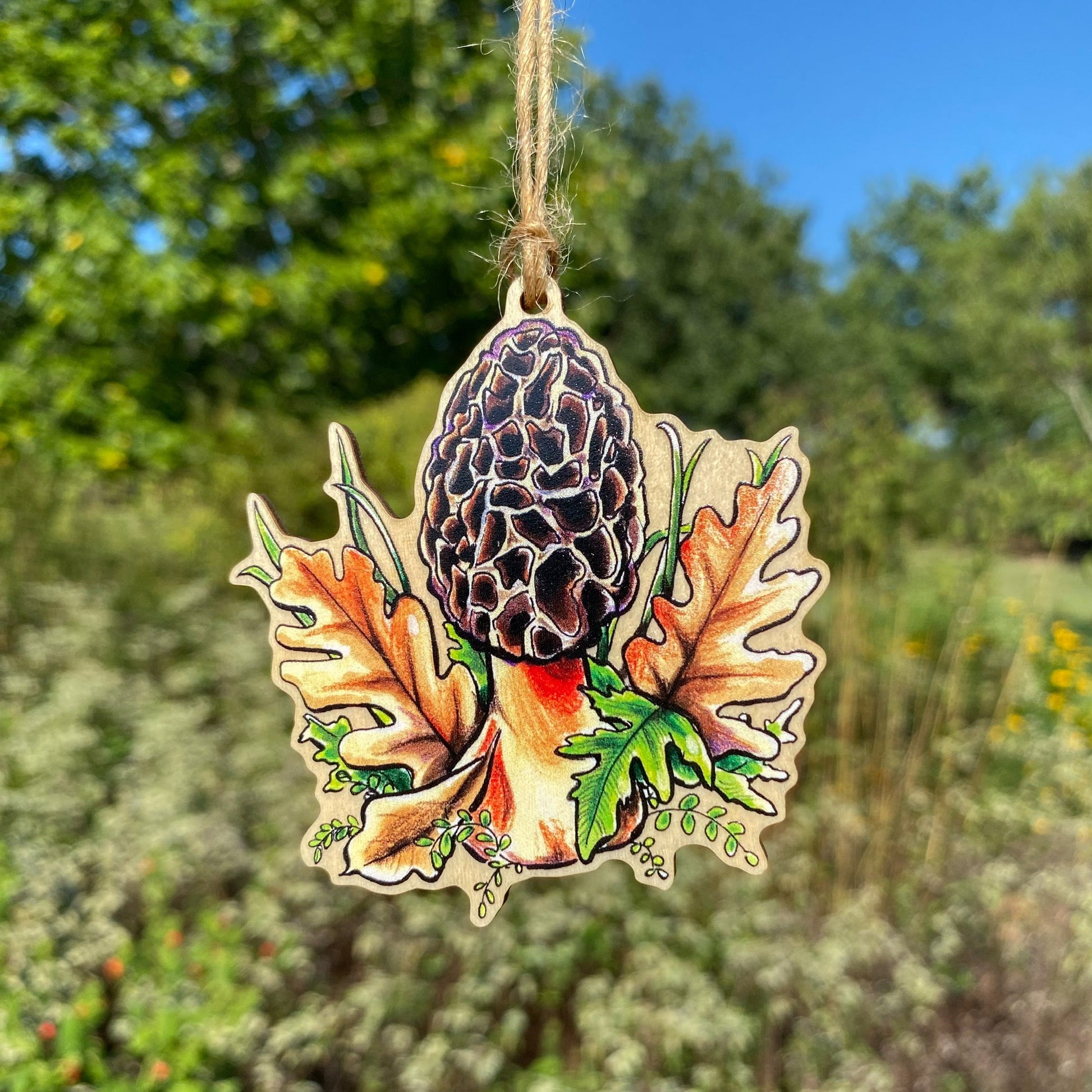 A wooden ornament strung with twine of a morel mushroom.