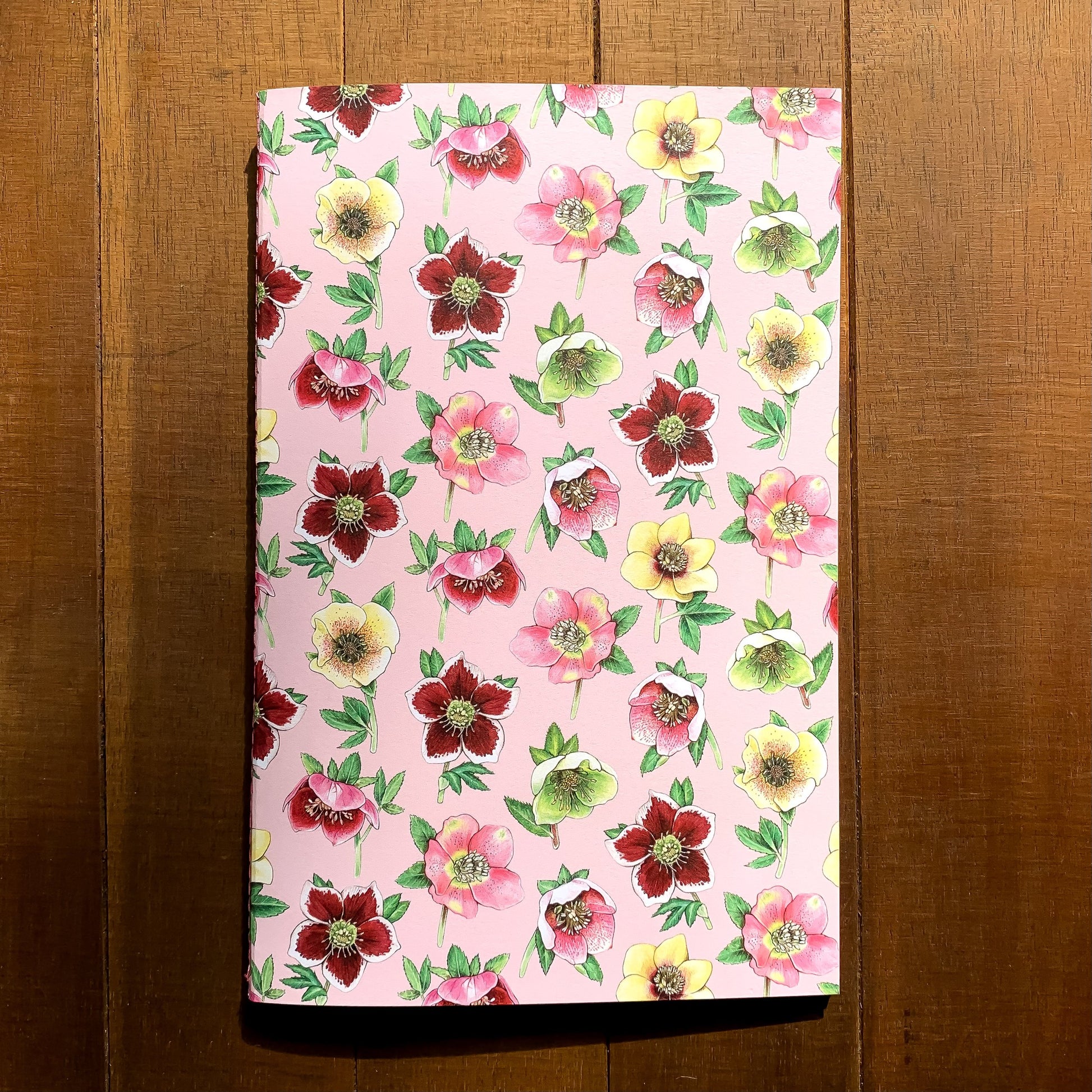 A handmade journal featuring a pattern of lenten roses on a pink background