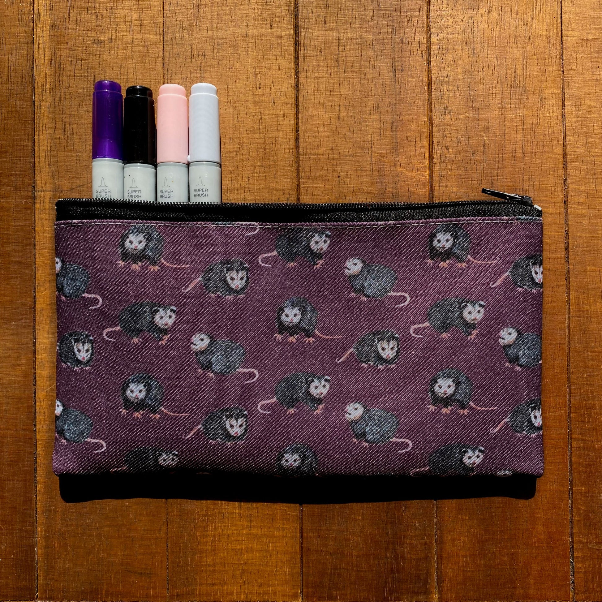 A purple zippered pouch featuring a pattern of opossums