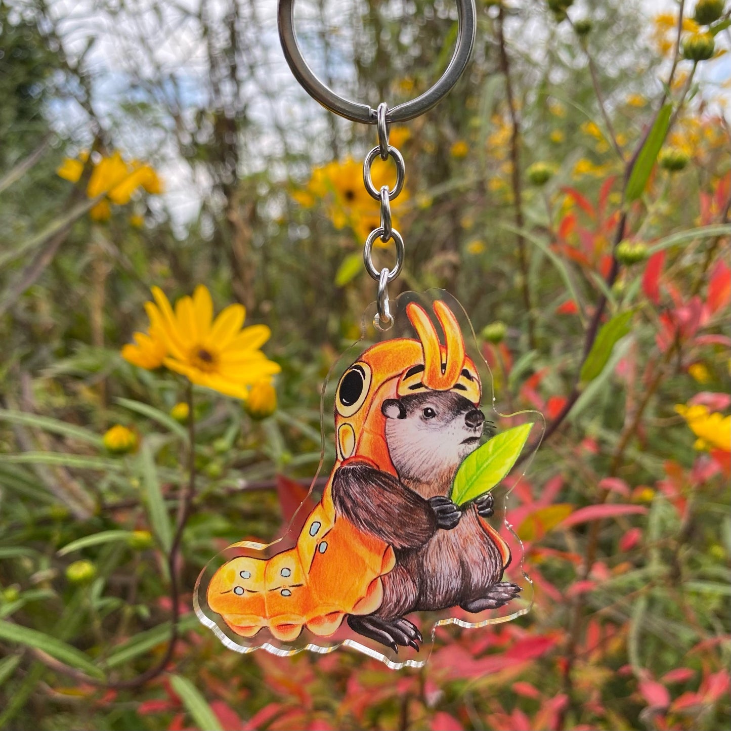 A keychain featuring an illustration of a groundhog dressed as a caterpillar