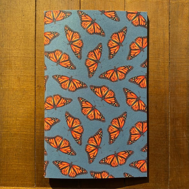 A handmade notebook featuring a pattern of monarch butterflies on a dark blue background